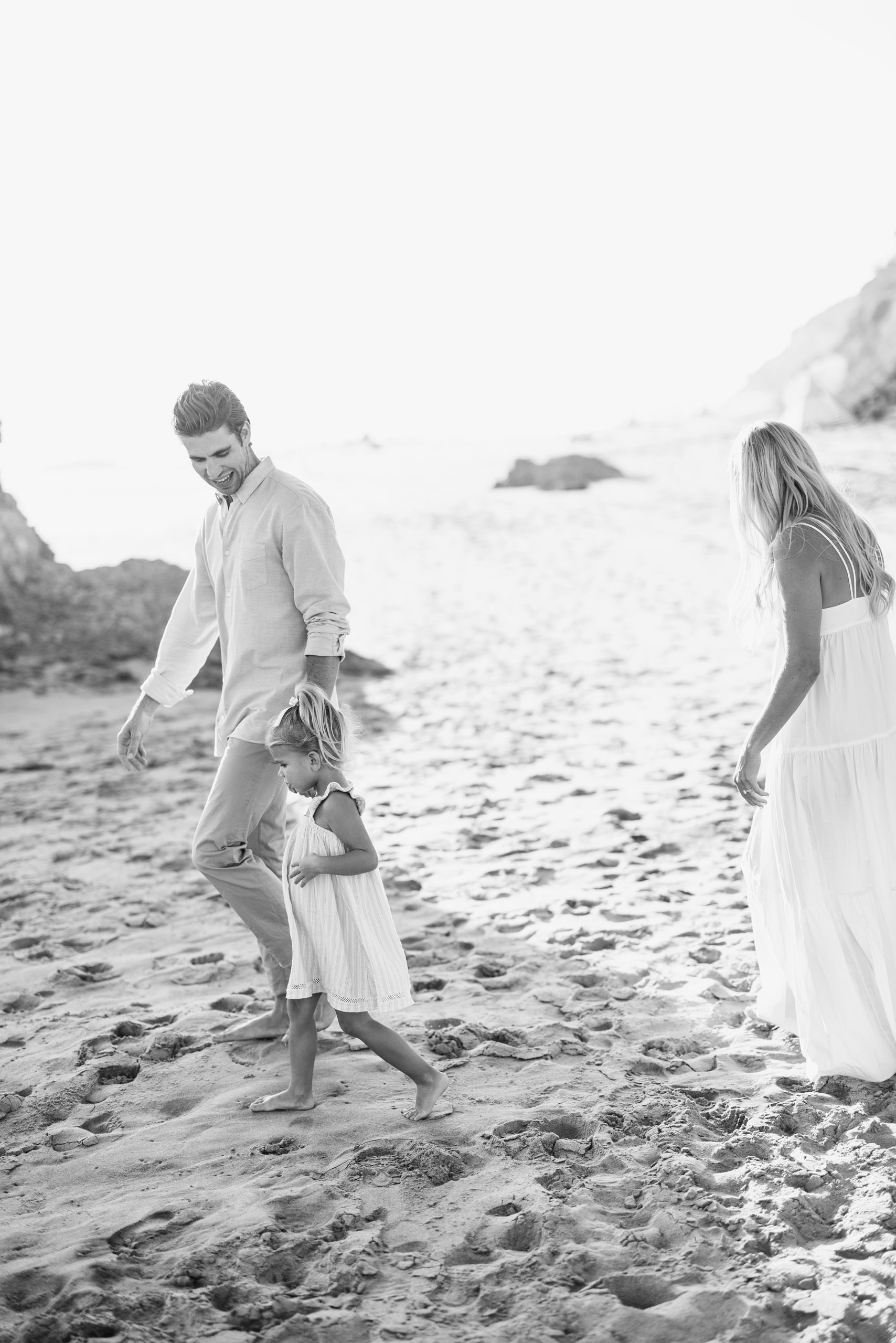black and white photo of family walking on the beach
